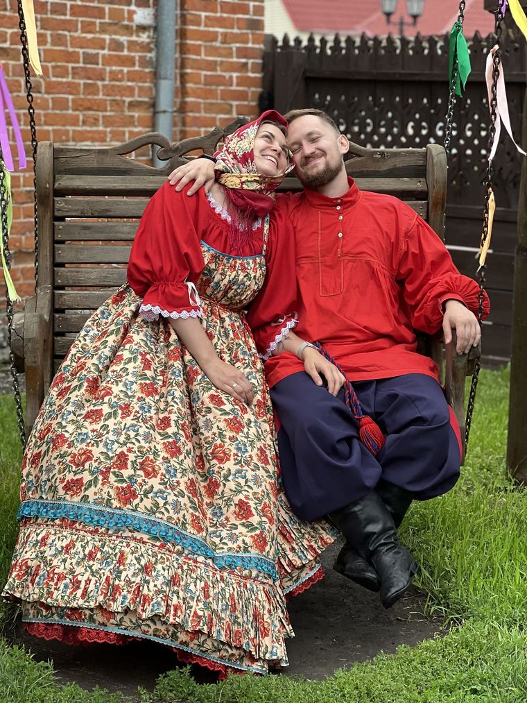 Роман с женой в народных костюмах на деревянных качелях